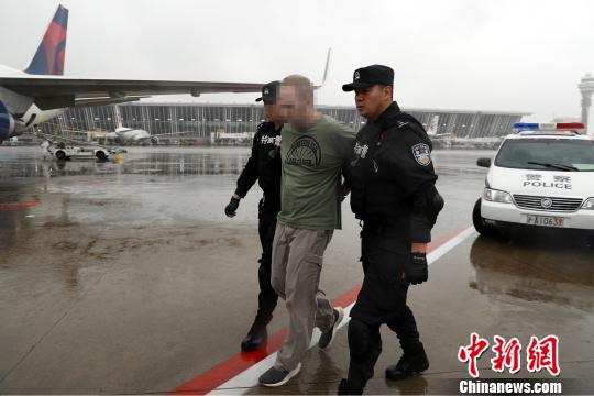 两名特警将美籍红通逃犯押送至机场。 张亨伟 摄