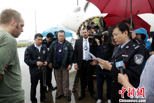 中国警方向美籍红通逃犯宣读驱逐出境相关文件。 张亨伟 摄