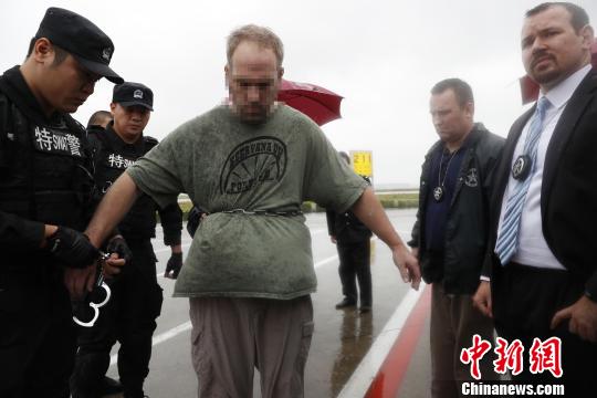 美籍红通逃犯被戴上手铐。 张亨伟 摄