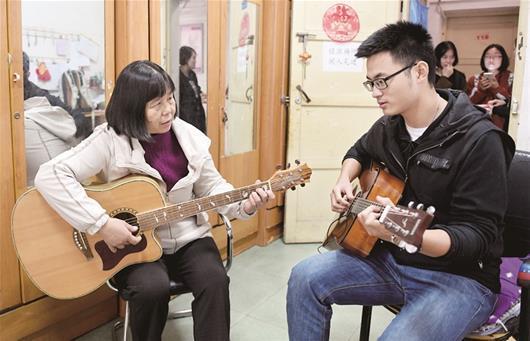 图为：周凡思同学教张传芸弹吉他