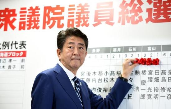 10月22日,在日本东京自民党总部,日本首相、自民党总裁安倍晋三为当选议员贴花。 新华社 图