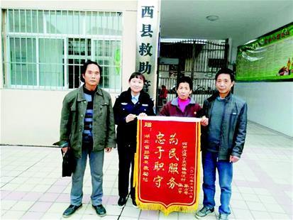 图为:张丰娥(右二)和家人给郧西救助站送锦旗
