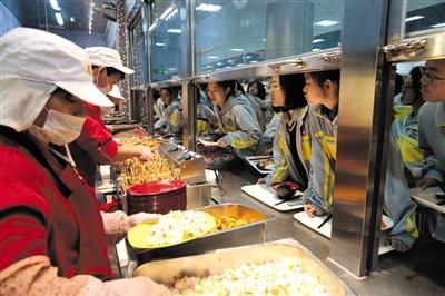 2017年10月19日,北京二中食堂的厨师们将准备好的午餐供应给学生们。