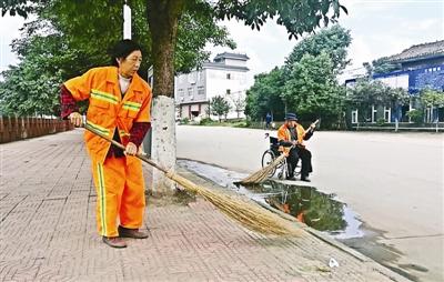 雷通兴坐着轮椅，陪着环卫工妻子薛桂兰清扫路面