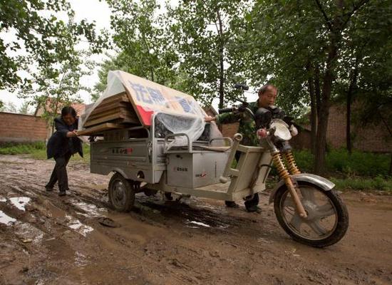 遇上下雨天，熊为义夫妇的三轮摩托车在乡村道路上行驶困难。邳州市司法局 供图