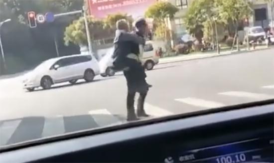 视频中交警何杰背着一位白发老人过斑马线。