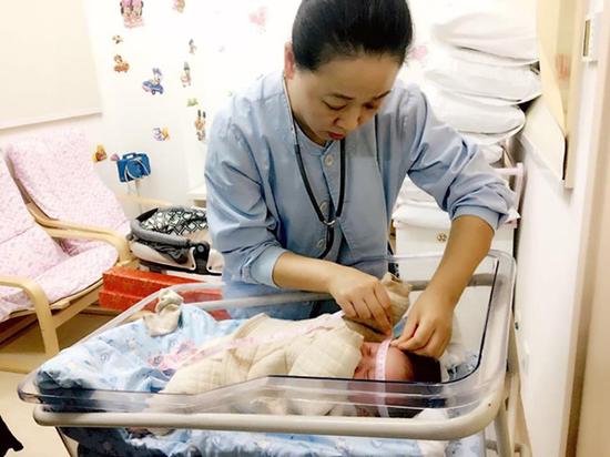 上海市第一妇婴保健院新生儿科副主任医师为延迟分娩32天的宝宝进行随访体检。