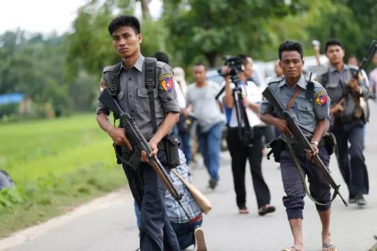 8月30日，在缅甸若开邦孟都地区，警察在被烧毁的房屋外警戒。