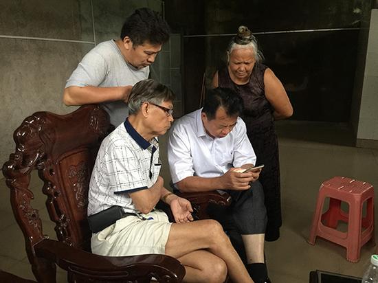 三户业主聚在杨美兰家一楼，讨论微信推送的强拆报道。