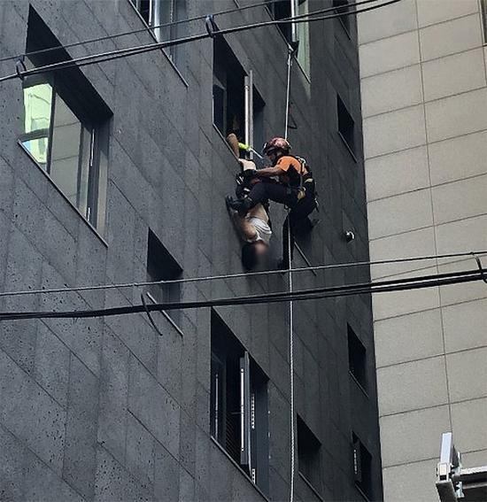 消防员正在解救倒挂窗外的女事主(《东亚日报》)