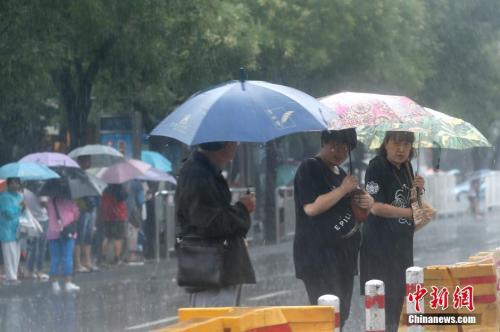 资料图:北京市民众冒雨出行。中新社记者 盛佳鹏 摄