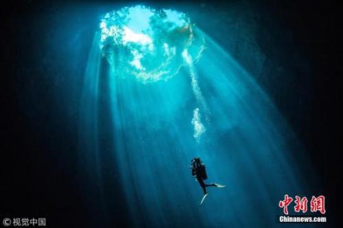 潜水员在一柱阳光中游泳。图片来源:视觉中国