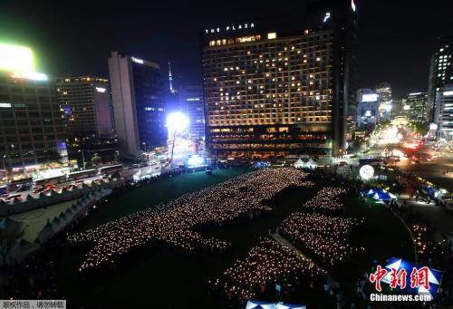 资料图:当地时间2015年4月17日,韩国首尔,4160名手举蜡烛的民众在首尔广场组成“世越号”船体的形状,纪念“世越号”客轮沉没一周年。