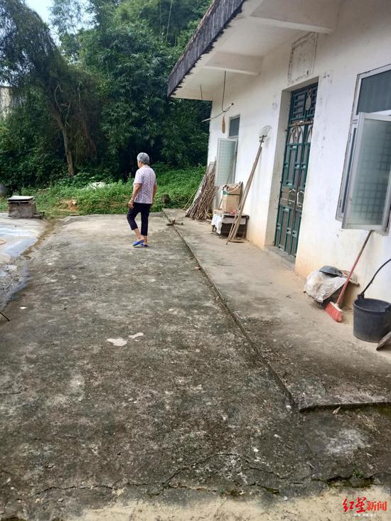 梁某华的母亲落寞地行走在屋前。