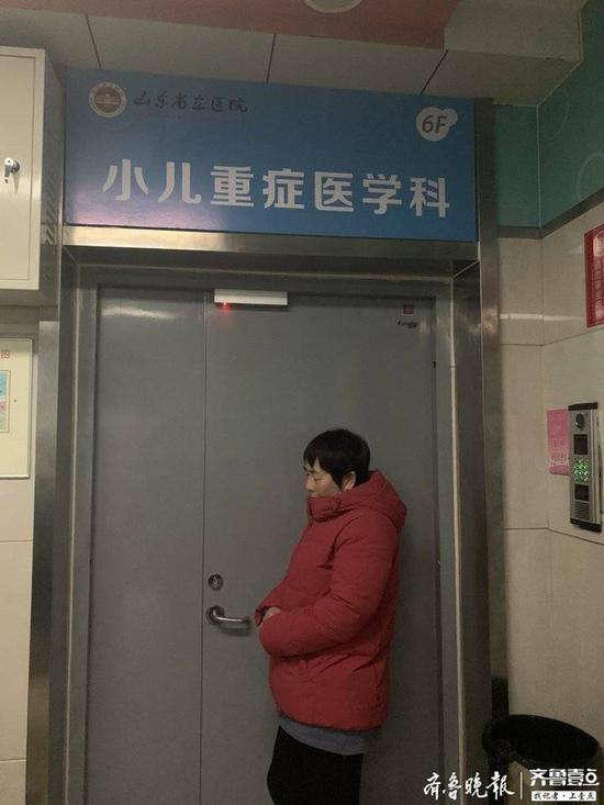 刘军芳（化名）倚在重症监护室大门前 。记者  李震  摄