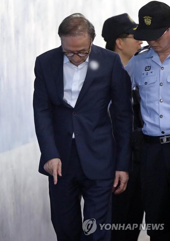 李明博走进法院前，突然用手指地