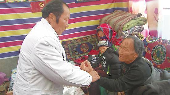 图为桑巴(左)正在家中为群众看病。记者 汪纯 摄