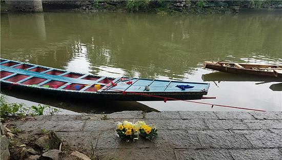 2018-06-19上午,有人在事发水域岸边摆上鲜花白酒祭奠遇难者。摄影:翟星理