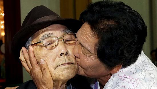 2015年10月26日，朝鲜金刚山，第20次韩朝离散家属团聚活动中，来自朝鲜的Koo Song Ok亲吻其来自韩国的父亲Koo Sang-yeon。图片来源：视觉中国