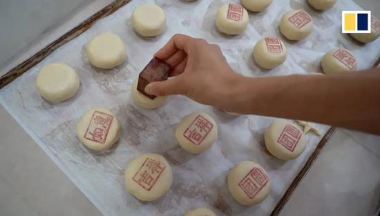 ▲建造者给月饼印字样(视频报导截图)