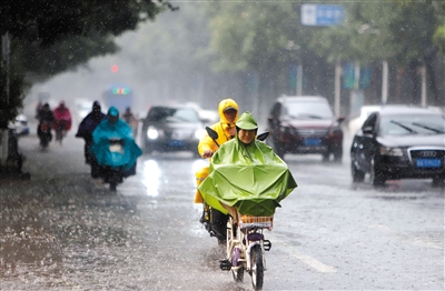 7月20日，石家庄，市民身着雨披在雨中骑行。本版图片/视觉中国