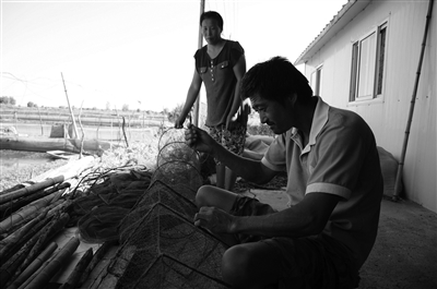 渔民正在织网等待恢复养殖。 薄云峰 摄