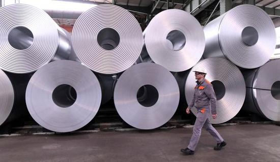 在德国萨尔茨吉特一家钢铁制品工厂，工人走过码放整齐的产品。（路透社）