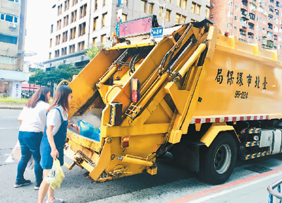 台湾民众将垃圾投入垃圾车内。柴逸扉摄