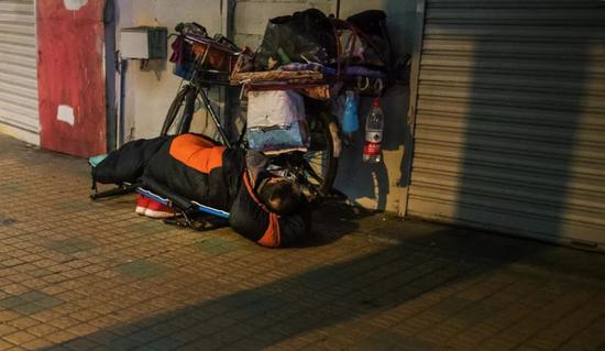 广州城中村里的流浪汉，睡着时把自行车放在身子内侧。受访者供图