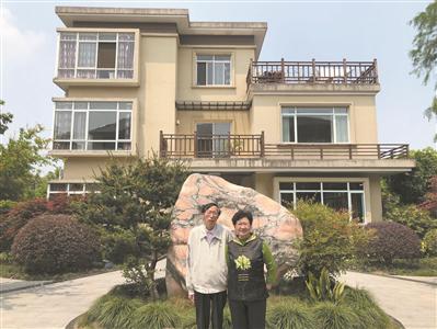 朱荣林和王桂芬站在自家的大别墅前。