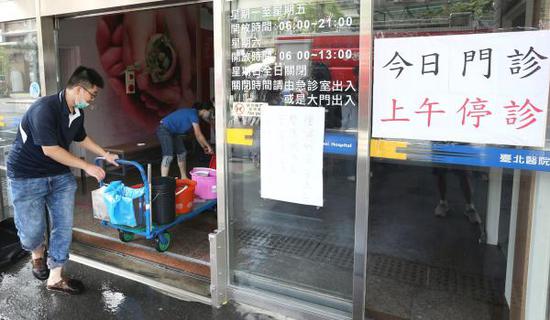 2018年8月13日，台湾新北，新庄台北医院贴出上午停诊公告，员工则忙于排除大厅内的积水。 udn.com侯永全/视觉中国 图