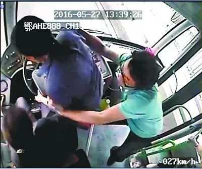 公交610路车上,男乘客吴烨(右)和司机(左)制止抢夺方向盘的女乘客(中)(视频截图)
