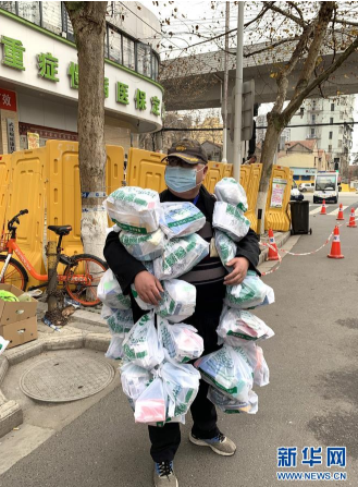在武汉市江岸区黄石路汉口大药房,惠民苑社区网格员丰枫把为住民购置的药挂在身上(2月24日摄)。 新华社发
