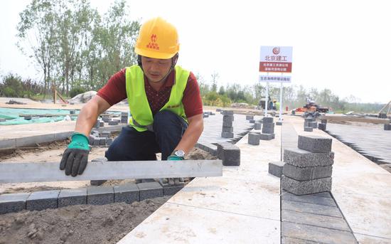 7月15日，北京市朝阳区温榆河公园施工现场，工人正在为步道铺设海绵砖。新京报记者 王嘉宁 摄