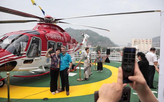 一对夫妇在船上的“雪鹰301”直升机前合影。新京报记者 王嘉宁 摄