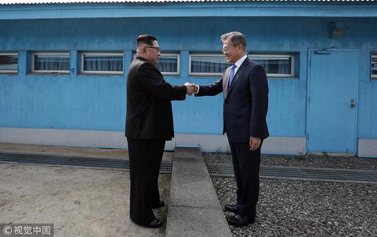 今年4月，朝鲜最高领导人金正恩和韩国总统文在寅在军事分界线握手。（视觉中国）