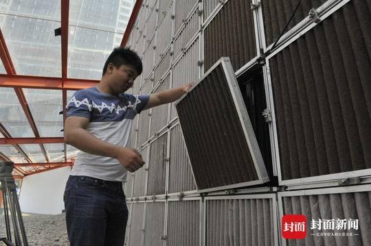 工作人员手中滤网,尚未清洗。附着的黑灰色尘土极为明显。