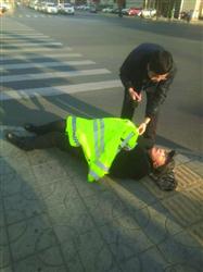老人摔倒在交警执勤的岗亭附近，交警脱下警服盖在老者的身上。　盘锦交警供图