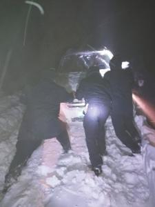 车陷雪中，民警徒手扒雪推车。