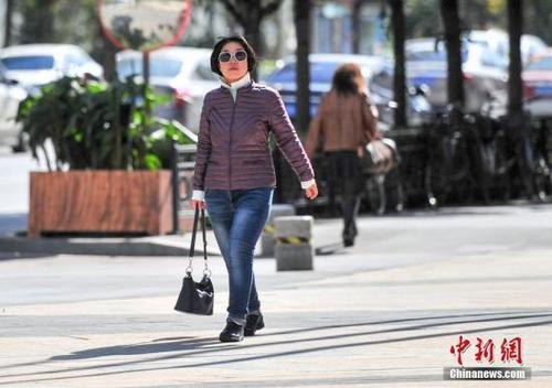 资料图:民众穿薄羽绒服出行。中新社记者 于海洋 摄