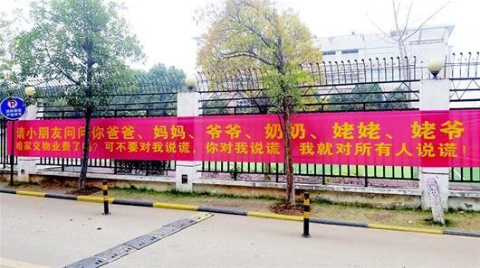 图为:物业在小区侧门附近悬挂横幅催缴物业费