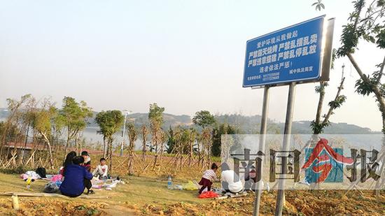 12月9日,环江滨水大道沿线,在“严禁烧烤”的宣传提示牌下,仍有市民在进行露天烧烤。 广西新闻网-南国今报 图