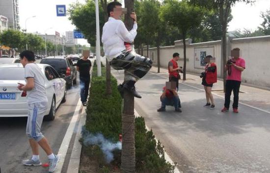 山东淄博,新郎被捆在路边大树上,脸上被涂抹牙膏、屁股上燃放鞭炮、脚上点烟。 视觉中国资料