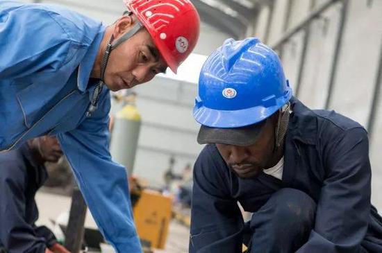 ▲中国工人和肯尼亚工人在中航国际的内罗毕工厂一起组装卡车。（美国《华尔街日报》网站）