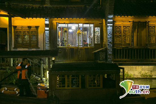 傍晚，乌镇景区内，前来参观的客人在店内用餐，窗外河面上一艘蓬船划过。中国青年网记者 宋继祥 摄