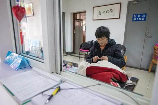 徐根娣在给学生缝补衣服。 记者 陈中秋 摄 (来源:都市快报)