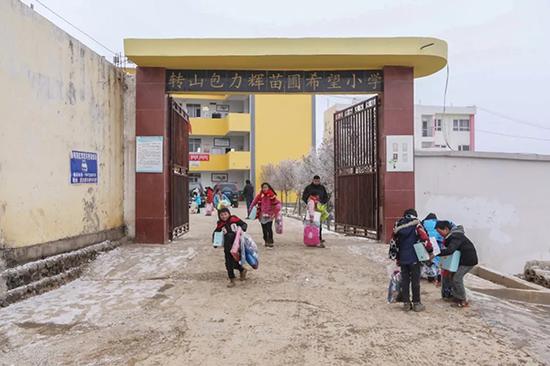 孩子领到爱心物资后,放学回家走出学校大门。