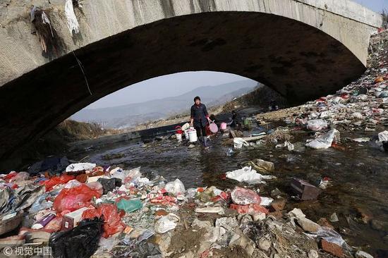 ▲2015年,大别山境内的一条河道的桥下布满各种生活垃圾。 图/视觉中国