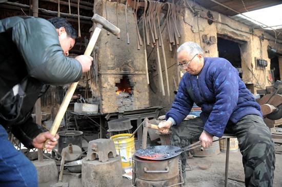父子两人在自家院中现场演示了一把铁锅的打造过程