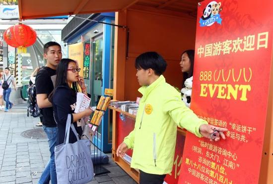 资料图:2015年10月6日是韩国首尔的中国游客欢迎日,中国游客在明洞进行旅游咨询。新华社记者姚琪琳摄